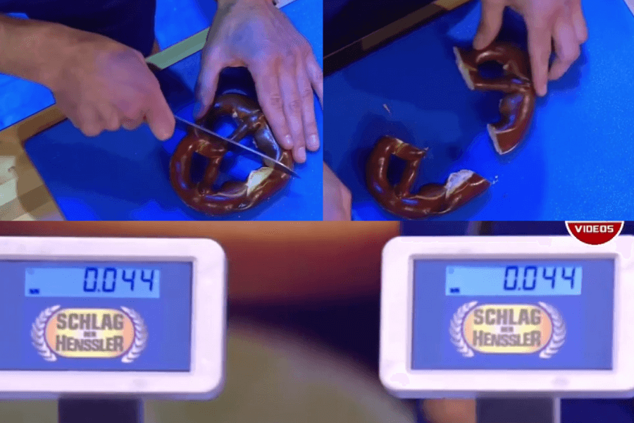 The image shows a contestant on the German game show Schlag den Henssler attempting to cut a pretzel precisely in half, with a digital scale below displaying the nearly identical weights of each half.