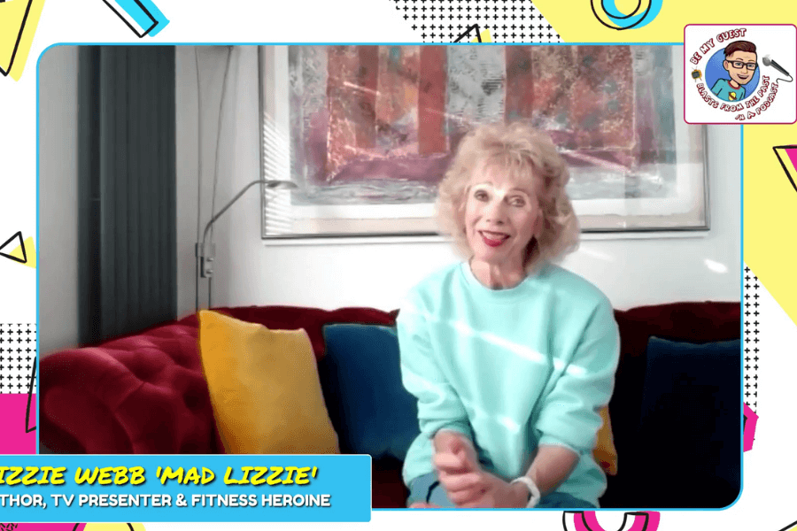 The photo shows Lizzie Webb, known as "Mad Lizzie," sitting on a colorful sofa wearing a light teal sweatshirt, smiling warmly, with a bright and cheerful background featuring bold retro graphics.