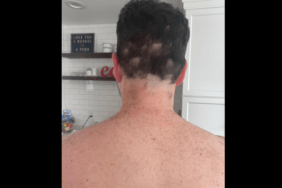 An ambitious DIY haircut leaves him with a patchy, uneven neckline, creating a look that’s part abstract art and part unfinished business in the back.