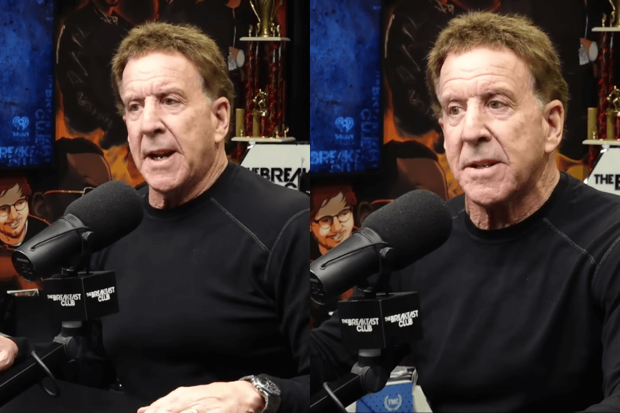 The photo shows a man with short brown hair wearing a black shirt, speaking passionately into a microphone during an interview in a radio studio, surrounded by colorful decorations and posters.