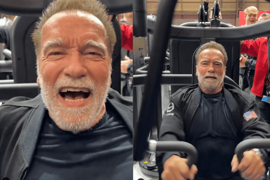 The photo shows an older Arnold Schwarzenegger intensely focused and energetic while working out on a chest press machine, surrounded by a lively gym environment with spectators and trainers in the background.