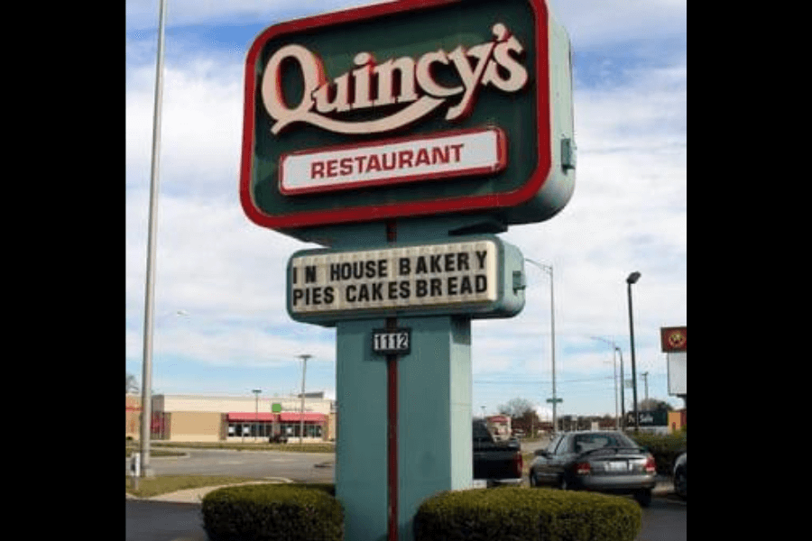 The image displays a Quincy's Restaurant sign featuring a marquee promoting its "In House Bakery" with pies, cakes, and bread. The retro design evokes memories of hearty meals and homemade baked goods.