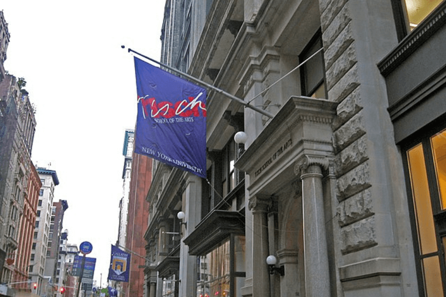 This image shows the exterior of the Tisch School of the Arts at New York University (NYU). The iconic purple flag with "Tisch School of the Arts, New York University" is prominently displayed, marking the institution's location in the heart of New York City. 