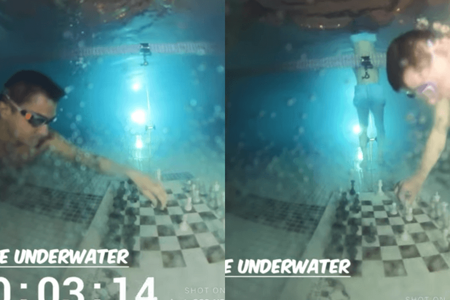 The image shows two contestants playing a game of chess underwater, with one participant holding their breath as they move pieces on a submerged chessboard, adding a unique and challenging twist to the classic game.