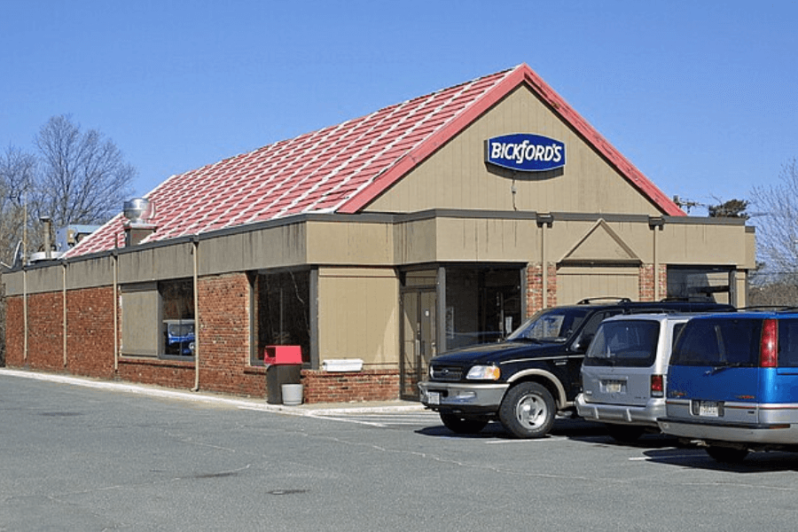 This photo shows a Bickford's restaurant, a once-popular family-style dining chain, featuring its signature sloped red roof and a parking lot with cars, evoking a sense of casual American dining nostalgia.