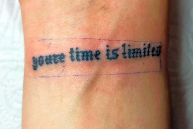 The photo shows a tattoo on someone's wrist that reads "youre time is limited," with a grammatical error where "you're" is incorrectly used instead of "your," accompanied by uneven lettering.