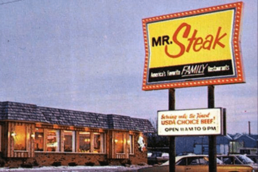 This image showcases a retro Mr. Steak restaurant, emphasizing its tagline as "America's Favorite Family Restaurants" and highlighting USDA Choice Beef on the signage. The classic design of the building and vintage cars in the parking lot evoke a nostalgic dining atmosphere.