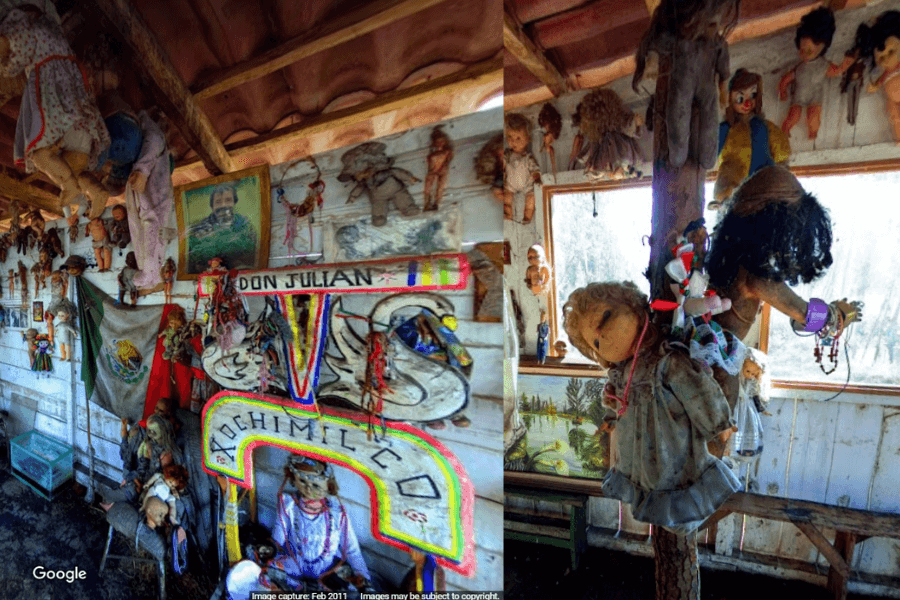 This image shows an eerie display of old, weathered dolls hanging in various positions around a rustic shack. The dolls, many of which are missing limbs or eyes, create a haunting atmosphere. Some are hanging from the ceiling by their necks, while others are nailed to the walls. 