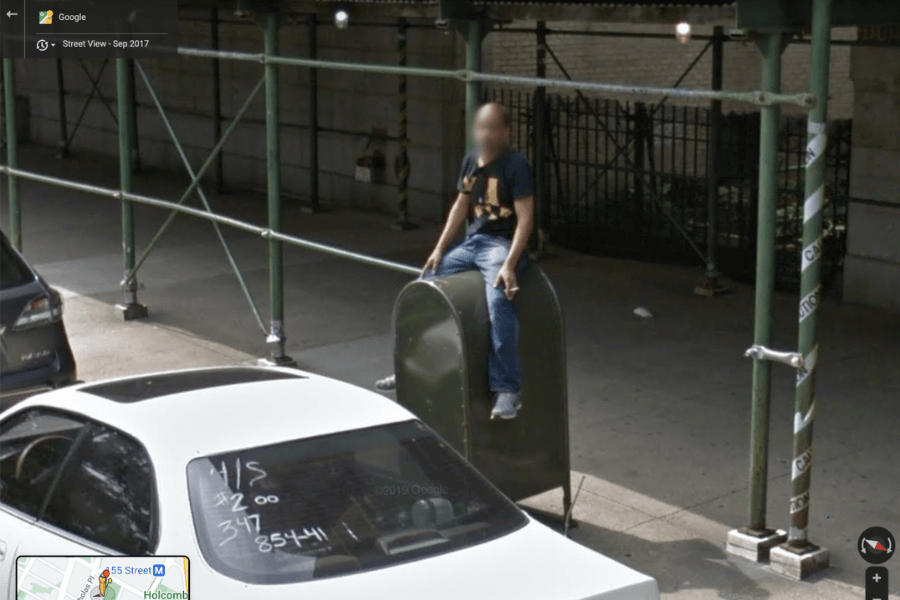 A man sitting on top of a sturdy USPS Mailbox