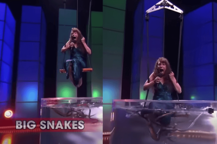 The image shows a terrified contestant suspended above a tank filled with large snakes on a game show. As she’s lowered closer to the snakes, her expression is a mix of fear and panic, holding a microphone as she prepares to endure this terrifying challenge. This setup likely tests contestants’ ability to perform under pressure while facing one of their worst fears.