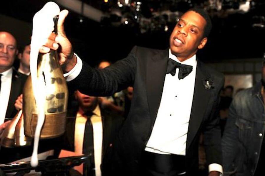 jay z wearing a tuxedo and holding a big champagne bottle 