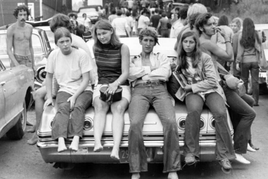 black and white picture of young people sitting on top of acar's trunk