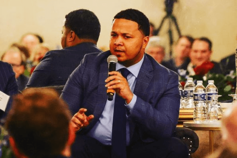 man speaking in front of people while sitting