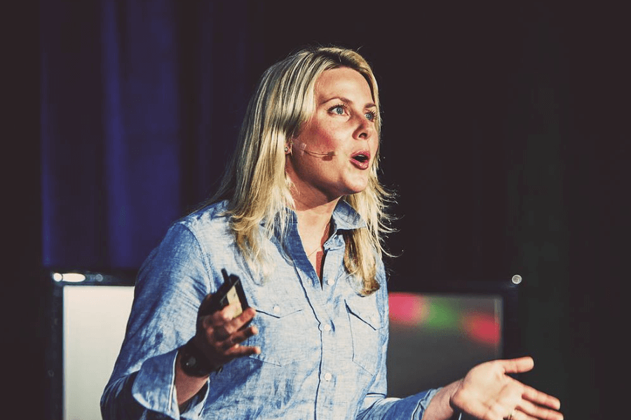 woman making a speech in front of TED audience