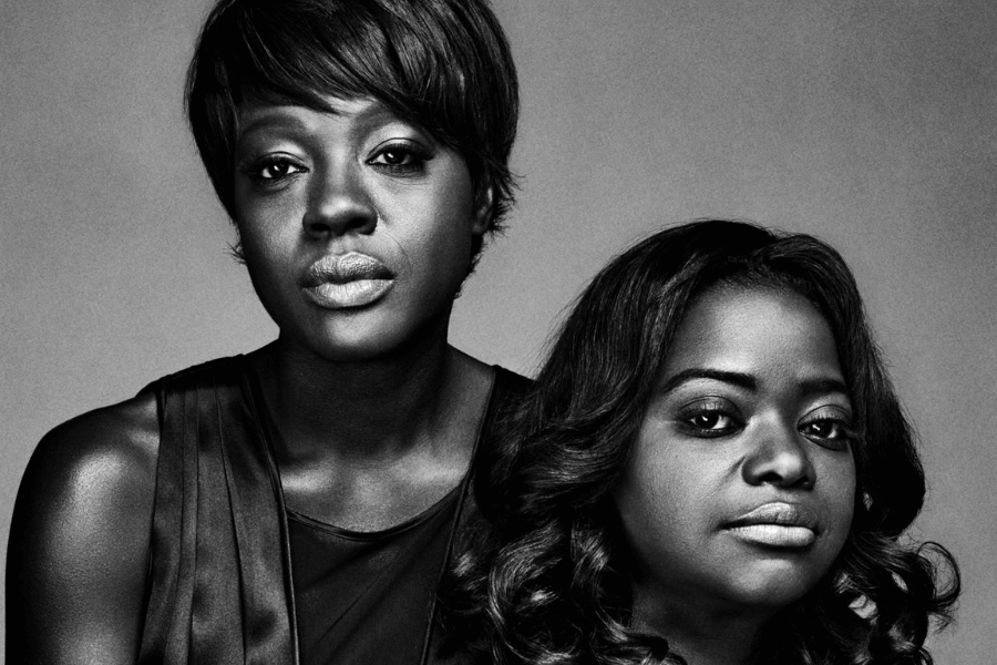 This black-and-white portrait features two women exuding strength and confidence. One has a short, sleek hairstyle and wears a sleeveless top, gazing directly into the camera with a serene yet powerful expression. The other, with wavy hair cascading down, also looks ahead with a poised demeanor. The minimalistic background enhances the focus on their faces and expressions, creating an impactful and elegant image. 