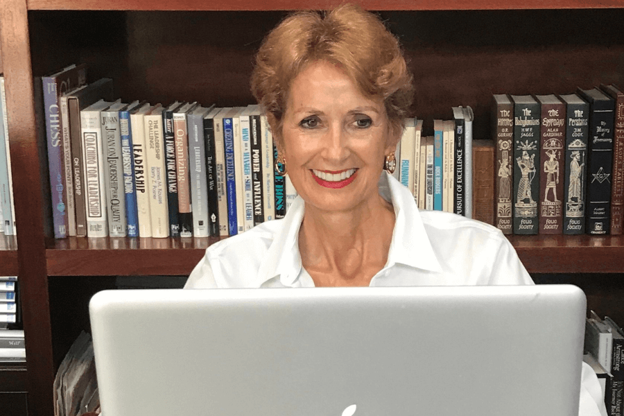 old woman smiling while working something on her laptop