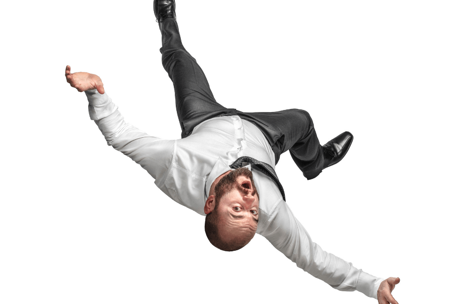 A bald man with a beard, dressed in a white shirt and black pants, appears to be falling or suspended in mid-air with his arms and legs flailing. His expression shows surprise and panic, and the background is completely white.