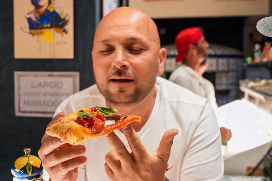 bold man holding pizza slice