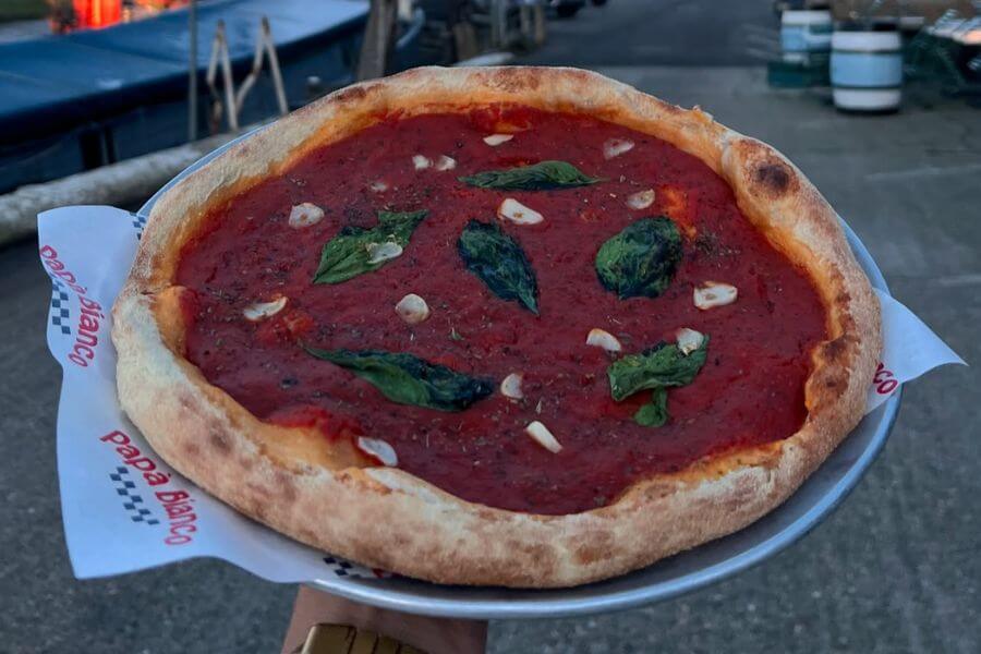 hand holding marinara pizza