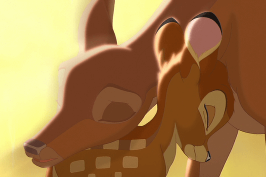 This image shows an animated scene featuring a doe gently nuzzling a fawn, both depicted in warm brown tones with a golden light in the background. The fawn has its eyes closed, leaning affectionately into the doe, creating a tender and nurturing moment. The soft lighting enhances the gentle and loving atmosphere of the scene.