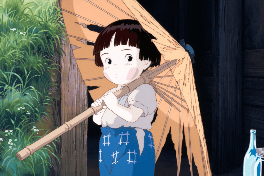 This image features a young animated girl holding a tattered parasol, standing in front of a rustic wooden structure. She has short, dark hair and is dressed in a simple outfit with a white blouse and blue patterned pants. The lush greenery in the background, combined with her thoughtful expression, adds a serene and nostalgic atmosphere to the scene.