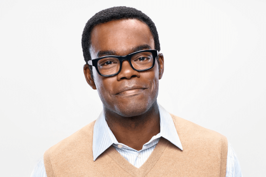 This image shows a man with a warm, friendly expression wearing thick-rimmed glasses and a beige sweater over a light blue collared shirt. The white background provides a clean and minimalistic setting, emphasizing his approachable demeanor. The overall tone is professional yet relaxed.