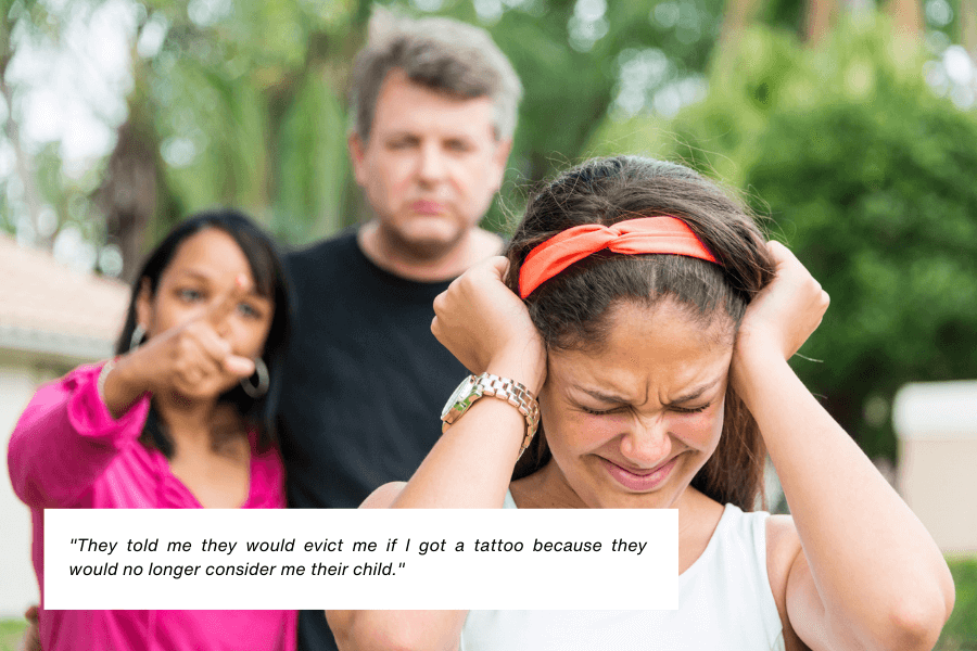 A young woman in a white top and orange headband covers her ears with her hands, looking visibly upset. Behind her, two adults, a man and a woman, point sternly at her, expressing anger or disappointment. The outdoor background is blurred, featuring trees and a house. Below the image, text reads: "They told me they would evict me if I got a tattoo because they would no longer consider me their child."