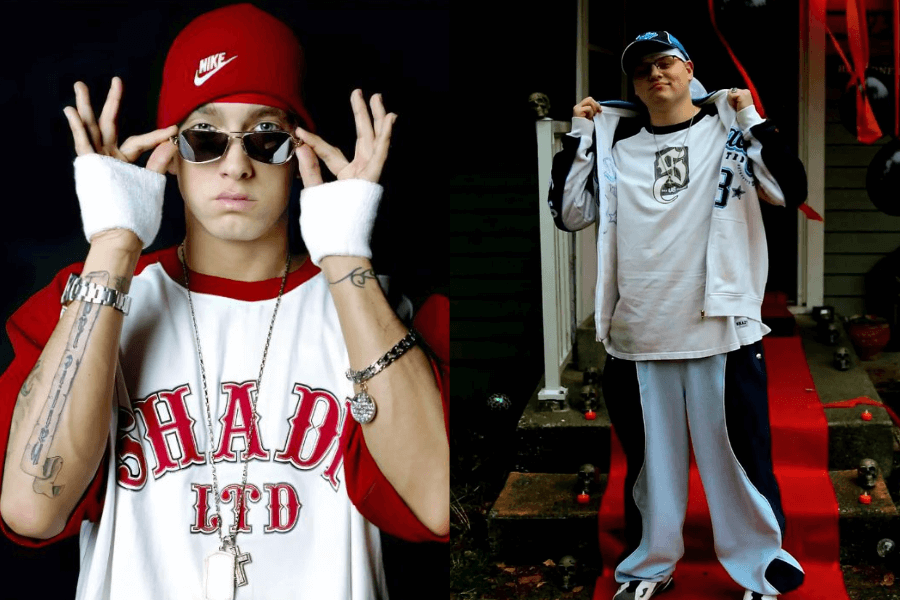 A side-by-side comparison of two individuals wearing early 2000s hip-hop-inspired outfits. On the left, a man in a red Nike beanie, oversized red and white "Shady LTD" jersey, silver chains, and sunglasses poses with a confident expression, accessorized with wristbands and a watch. On the right, another individual replicates the Y2K rap aesthetic with a white and navy tracksuit, an oversized graphic T-shirt, a cap, and a chain, standing on a red carpeted entrance with Halloween decorations in the background. Both outfits reflect the bold, baggy, and flashy hip-hop fashion of the era.