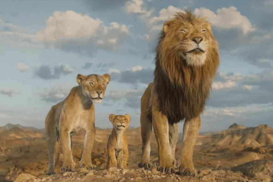 A majestic lion stands proudly with a lioness and a young cub beside him, gazing into the distance. The golden savanna landscape stretches behind them, with a sky dotted with soft clouds. Their detailed, lifelike fur and expressive faces create a sense of realism and grandeur.