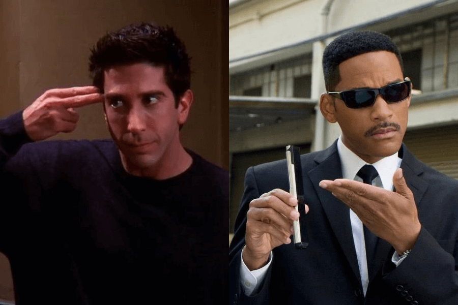 A side-by-side image of two well-known characters in contrasting moods. On the left, a man with dark hair wearing a black sweater makes a sarcastic gesture, pointing his fingers to his temple as if mimicking a gun, with an exasperated expression in a dimly lit room. On the right, a man in a black suit, white shirt, and black tie, wearing dark sunglasses, holds a futuristic memory-erasing device and gestures as if about to use it in an urban setting.