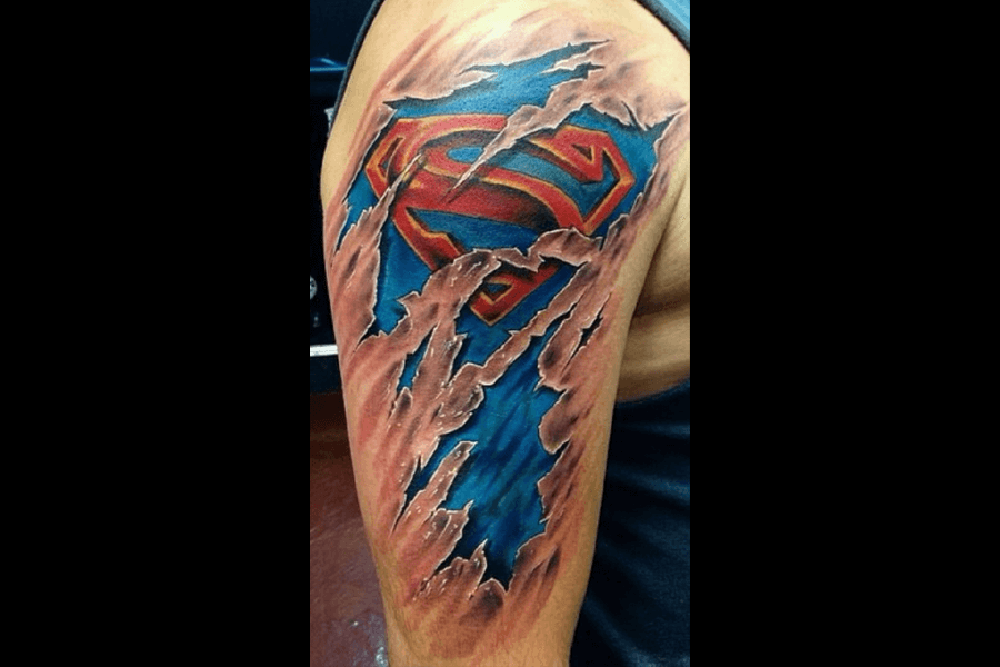 A tattoo of a ripped-skin effect revealing a Superman logo underneath. The design creates the illusion of the skin tearing to expose the superhero emblem and a blue suit.