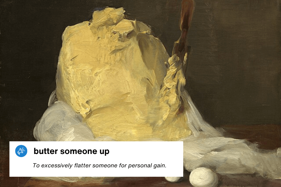 A classic oil painting of a large, textured mound of butter with a wooden butter paddle sticking out, surrounded by a white cloth and eggs. A text overlay in the bottom left corner reads: "Butter someone up – To excessively flatter someone for personal gain."