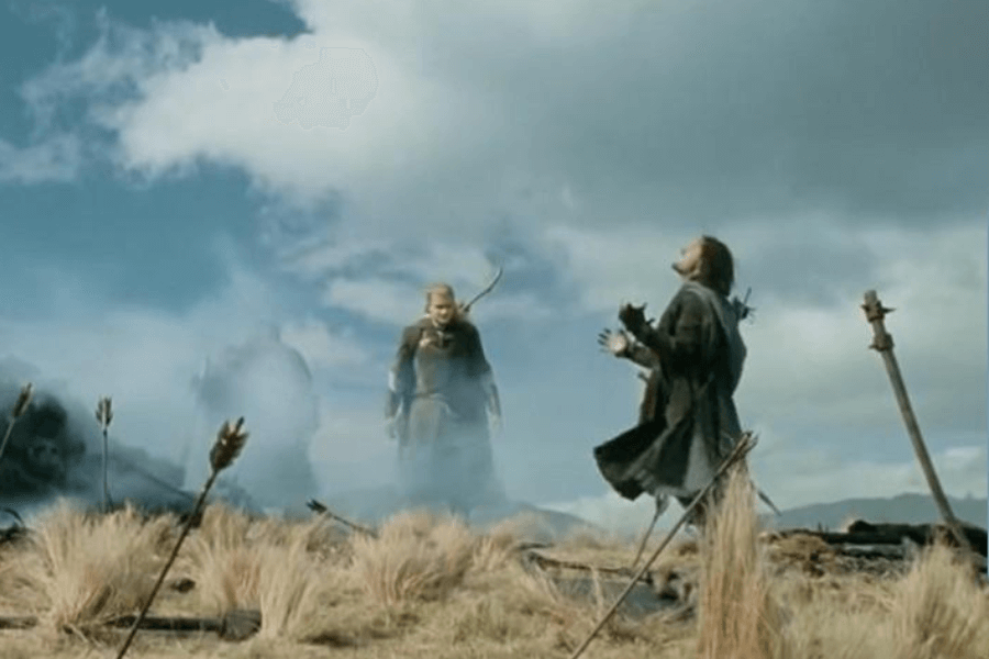 A warrior collapses to his knees in a battlefield surrounded by tall grass, arrows, and smoke. His arms are open, and his head tilts back in agony, while another warrior with a bow stands in the background, watching solemnly. The sky above is filled with dramatic clouds, emphasizing the intensity and emotion of the scene.