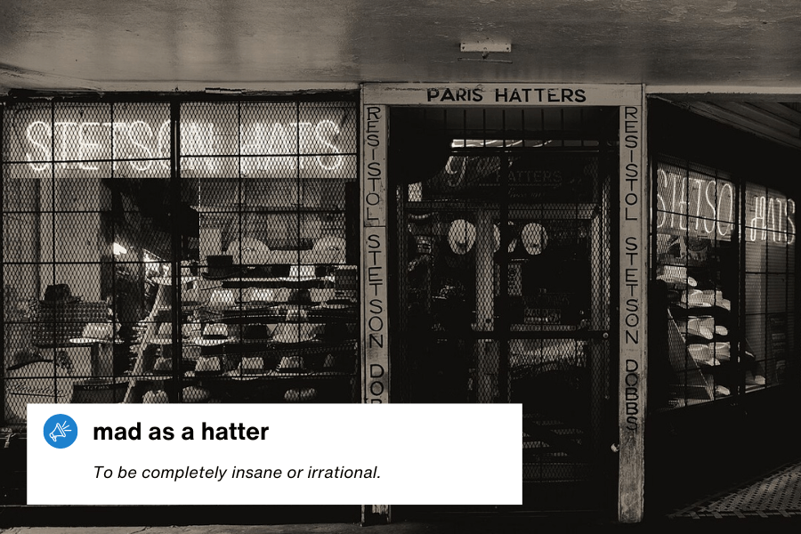 A black-and-white photograph of a vintage hat shop named "Paris Hatters," with a gated storefront displaying various hats and neon signs that read "Stetson Hats." A text overlay in the bottom left corner reads: "Mad as a hatter – To be completely insane or irrational."