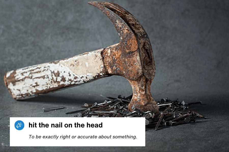 A close-up of an old, rusted hammer resting on a pile of scattered nails against a dark, textured background. The worn-out tool suggests years of use in construction or repair work. A text overlay in the bottom left corner reads: "Hit the nail on the head – To be exactly right or accurate about something."