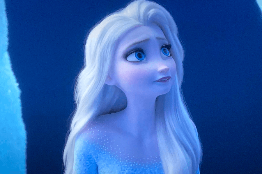 A beautifully animated ice queen with long, flowing platinum blonde hair gazes upward with a gentle, hopeful expression. She wears a shimmering, ice-blue dress with sparkling details, set against a deep blue background that evokes a frozen, magical atmosphere.