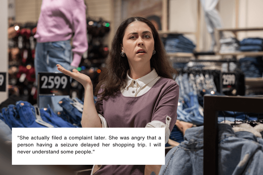 This image shows a woman standing in a clothing store, gesturing with one hand and appearing visibly frustrated or confused. The background includes racks of denim jeans and price tags. The quote in the image reads: "She actually filed a complaint later. She was angry that a person having a seizure delayed her shopping trip. I will never understand some people."