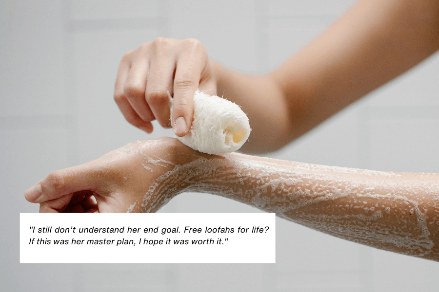 This image shows a close-up of a person using a loofah to scrub their soapy forearm, with a clean, white-tiled background suggesting a bathroom setting. The quote in the image reads: "I still don’t understand her end goal. Free loofahs for life? If this was her master plan, I hope it was worth it."