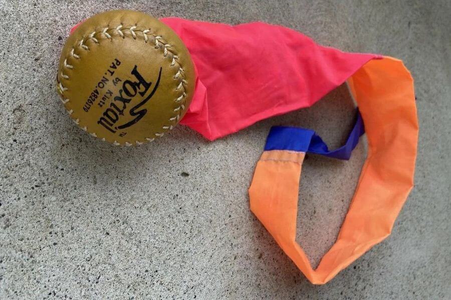 A baseball ball attached to pieces of colorful fabric with the shape of a tail