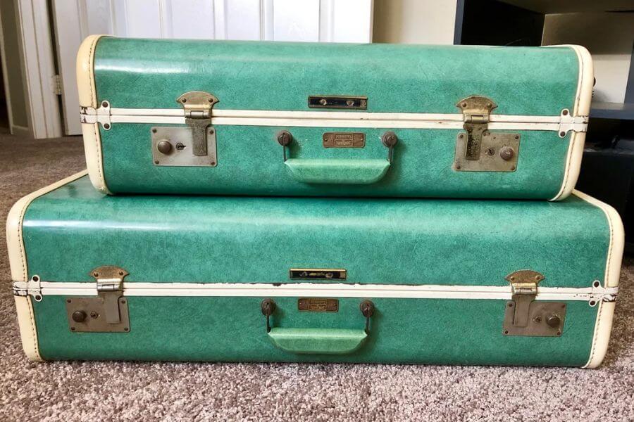 The photograph shows a pair of vintage green suitcases stacked neatly on a carpeted floor. Their textured exterior, accented by cream-colored trim and brass hardware, exudes classic mid-century travel charm. Sturdy handles and secure metal latches suggest these cases have seen many adventures. With their retro aesthetic, they carry the nostalgia of train rides, road trips, and old-fashioned elegance.





