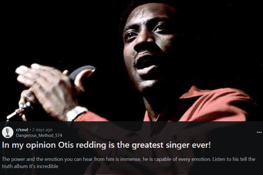 A male soul singer passionately performs on stage, wearing a deep red shirt with sleeves rolled up. He grips the microphone while clapping his hands, his face glistening with sweat and filled with raw emotion. The dark background emphasizes his intense presence under the stage lighting.