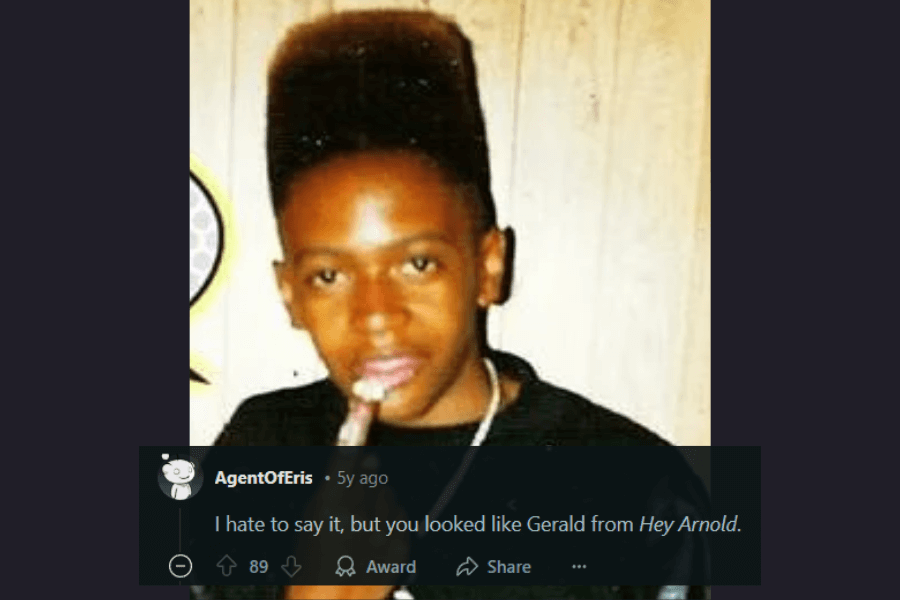 A vintage photograph of a young man sporting a high-top fade hairstyle, a popular look from the late 80s and early 90s. He is wearing a black shirt, a silver chain, and holding an object near his mouth, possibly posing for the camera with a casual expression. The comment below humorously compares his hairstyle to Gerald from Hey Arnold!.