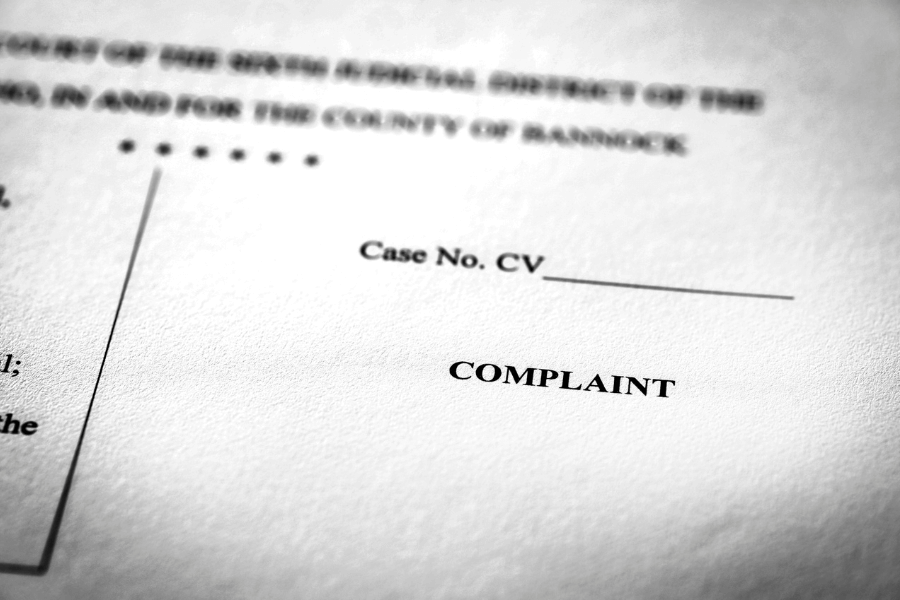 A close-up of a legal document with the word "COMPLAINT" printed in bold, indicating a formal lawsuit filing. The document includes a case number field labeled "Case No. CV ____" and partially visible text from a court header. The black-and-white image emphasizes the seriousness of the legal process.