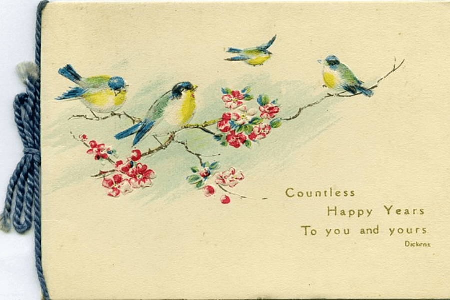 A vintage greeting card featuring an illustration of four small yellow and blue birds perched on a blossoming branch with pink flowers. The card has a soft beige background and is tied with a blue cord on the left side. The message on the right reads, "Countless Happy Years To you and yours. Dickent."