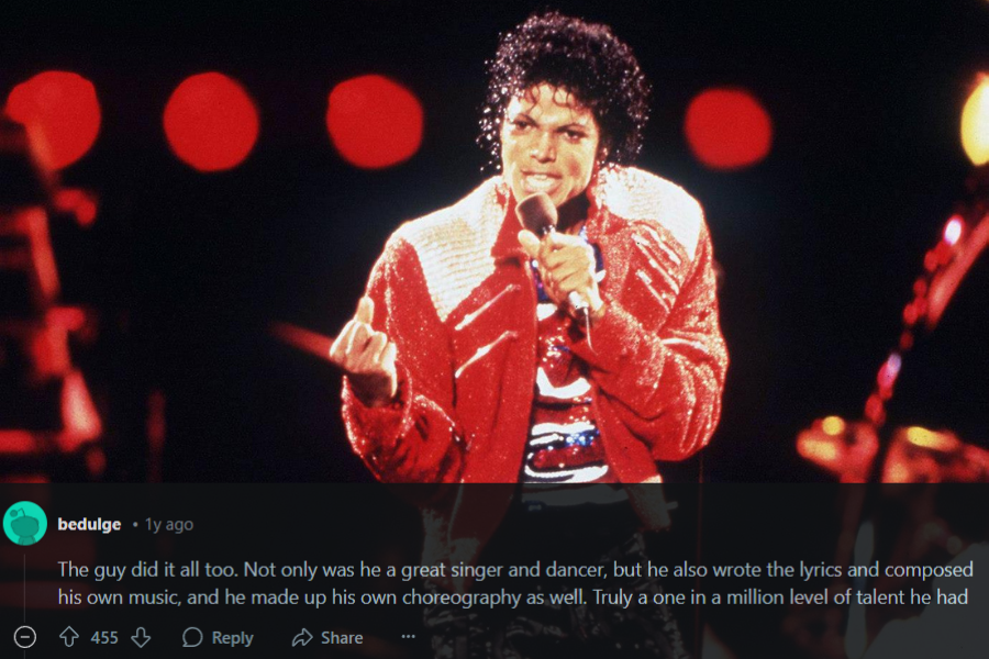 A dynamic concert photograph of a male performer dressed in a sparkling red and white jacket, black pants, and a sequined shirt. He holds a microphone in one hand while gesturing with the other, his curly hair glistening under the stage lights. The background is filled with red circular lights, creating a dramatic and energetic atmosphere.