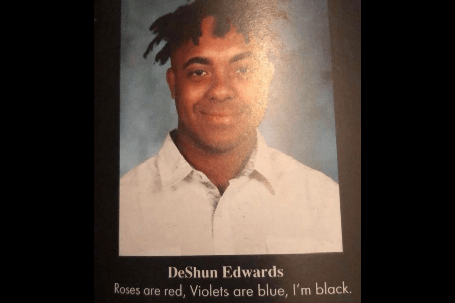 A high school yearbook photo of a young man with short, twisted hair, wearing a white collared shirt against a blue background. Below his name, "DeShun Edwards," his yearbook quote humorously reads, "Roses are red, Violets are blue, I'm black."