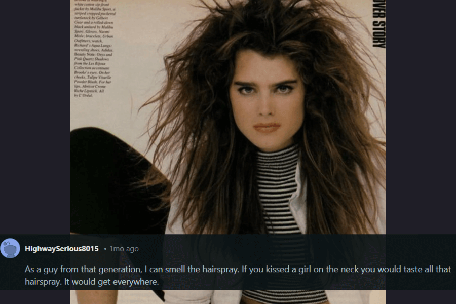 A striking 1980s fashion magazine-style portrait of a woman with intensely voluminous, teased hair that extends wildly in all directions. Her thick eyebrows and bold gaze give her an iconic, confident look, complemented by a black-and-white striped turtleneck and a white jacket. A humorous comment below reminisces about the overwhelming presence of hairspray in that era, joking that it could even be tasted when kissing someone.