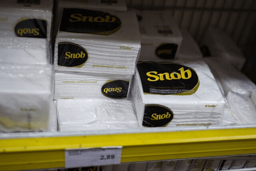 Several packs of "Snob" brand paper napkins stacked on a supermarket shelf with a yellow price tag displaying "2,89." The packaging is predominantly white with a black and gold logo, and the napkins appear thick and high-quality.