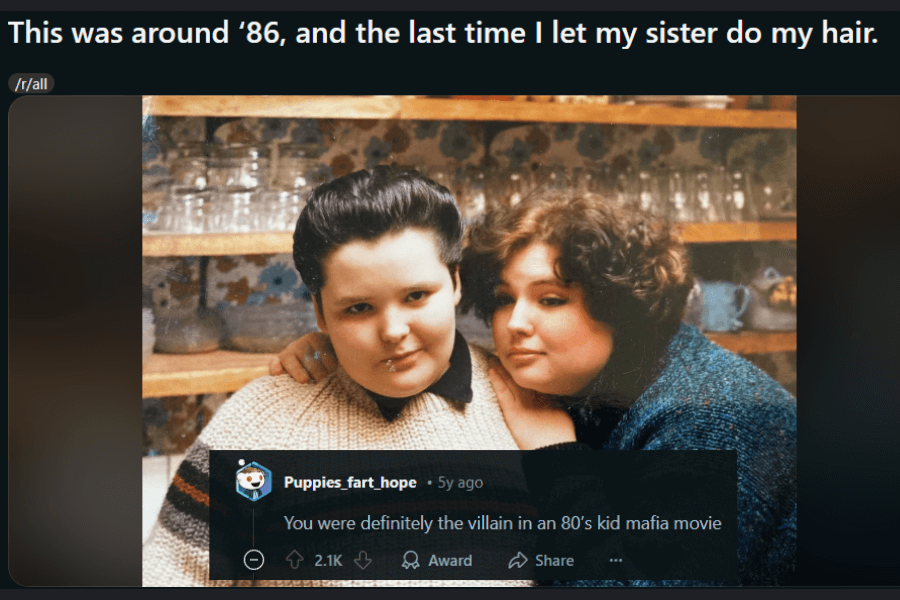 A vintage 1980s photo of two siblings posing in a cozy kitchen setting. The person on the left has slicked-back hair, a confident smirk, and a piercing, giving off a tough, no-nonsense vibe. The sibling on the right has voluminous, curly hair and leans in with a knowing expression. The caption humorously laments letting a sister do their hair, while a comment below jokes that they look like a villain from an 80s kid mafia movie.