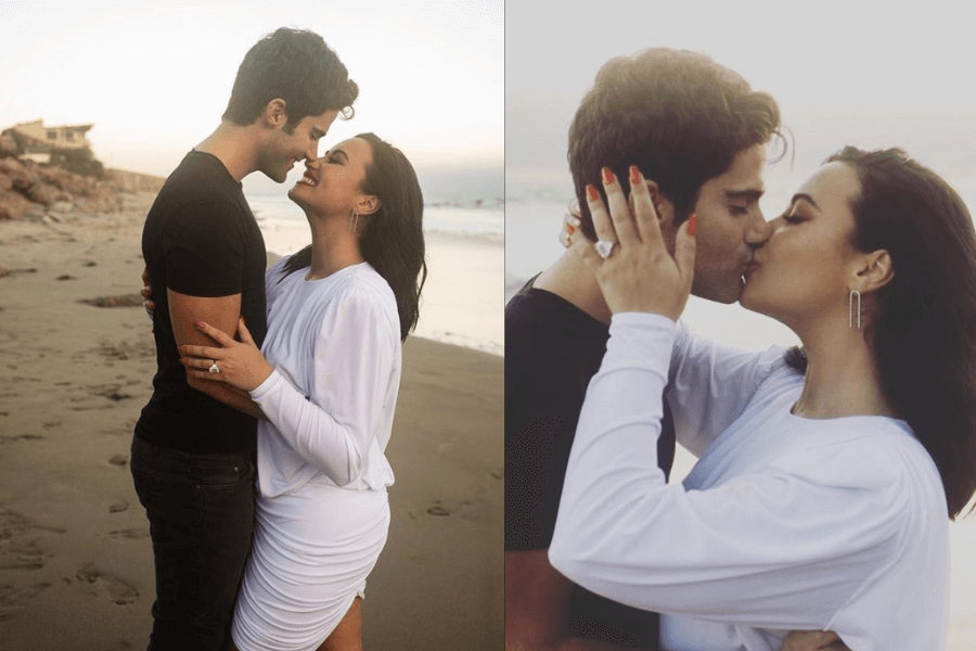 A romantic couple embraces on a sandy beach during sunset. The left image captures them smiling at each other closely, with the woman wearing a white dress and the man in a black T-shirt and jeans. The right image shows them kissing, with the woman’s hand resting on his face, displaying a large engagement ring. The ocean waves and soft lighting add to the dreamy atmosphere.